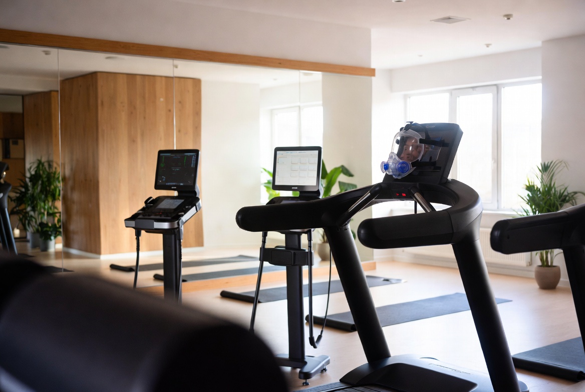 The Vitalis Lab studio: metabolic testing console and treadmill with a VO₂max mask, in a bright, plant-filled room